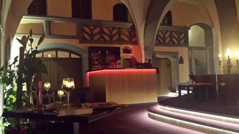 Die Theke am Abend, warm beleuchtet, davor Gläser und Kerzenleuchter.