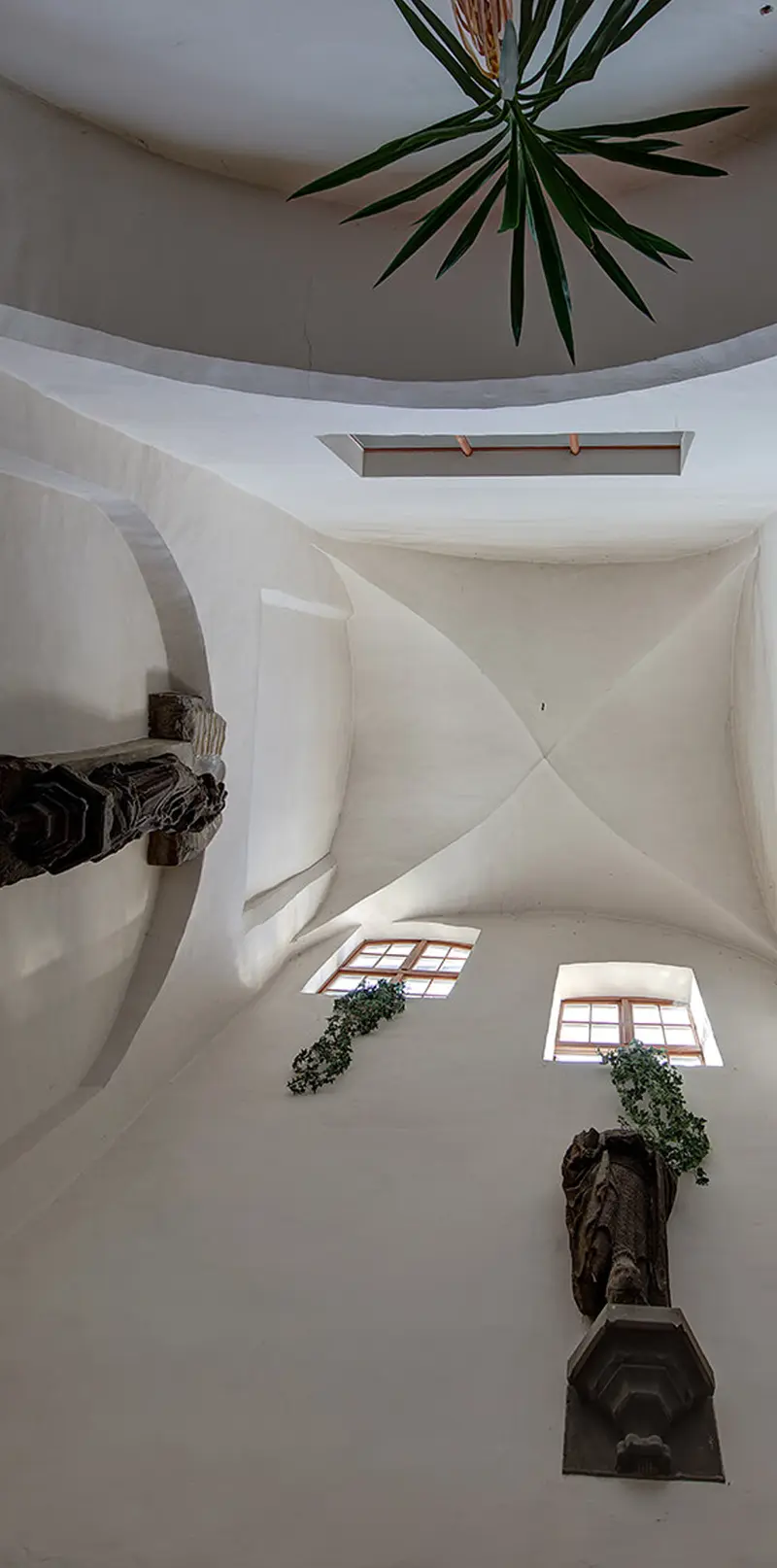 Blick in den oberen Lichthof mit hellem Kreuzgewölbe; an der Wand zwei verwitterte, überlebensgroße Sandsteinfiguren.